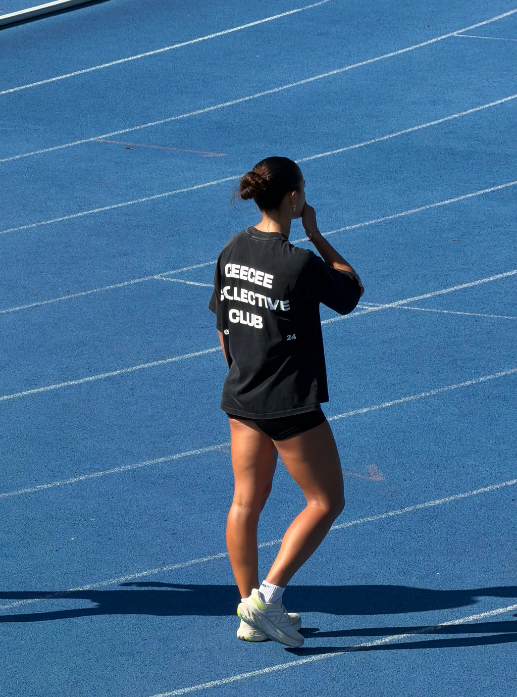 Person wearing a black t-shirt with text on a blue track